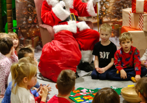 Dzieci siedzą obok Mikołaja.