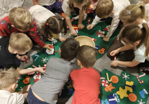 Przedszkolaki ozdabiają filcowe choinki.