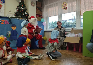 Mikołaj rozdaje dzieciom prezenty.