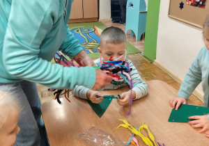 Pani prowadząca zajęcia rozdaje dzieciom materiały.