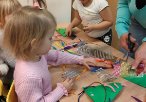 Dziewczynki przy stoliku ozdabiają choinki.