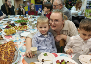Dzieci i rodzice siedzą przy stole wigilijnym.