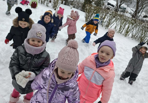Przedszkolaki stoją w zimowym ogrodzie.