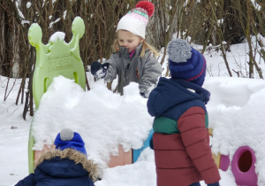 Przedszkolaki bawią się śniegiem.