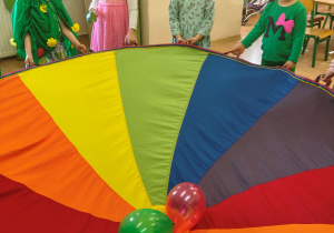 Przedszkolaki bawią się chustą animacyjną i balonami.