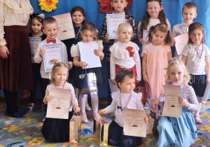 Nagrodzeni uczestnicy stoją z dyplomami i nagrodami oraz organizatorką konkursu