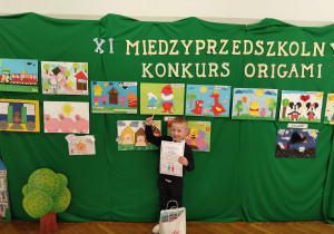 Miłosz na tle prac konkursowych wskazuje swoją pracę.