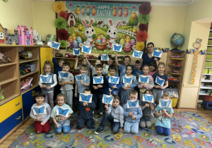 Dzieci trzymają w rączkach swoje prace- niebieskie motyle na patyczkach.