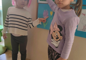 Dziewczynki pokazują wiosenne owady i rośliny.