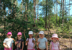 Dziewczynki z kijkami w lesie.