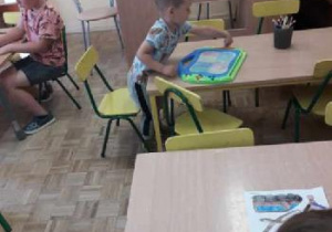 Chłopiec rysuje przy stoliku.
