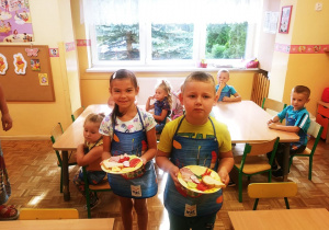 Chłopiec i dziewczynka prezentują talerze z warzywami.