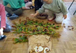 Dzieci układają drzewo z materiału przyrodniczego.