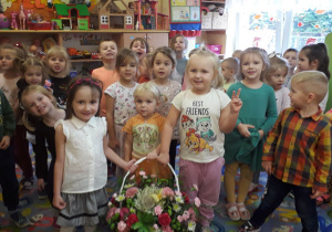 Przedszkolaki wręczają kosz kwiatów.