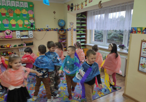 Dzieci tańczą w płaszczach przeciwdeszczowych.