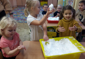 Dzieci lepią lody ze śniegu.