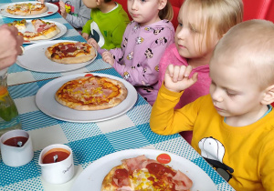 Dzieci jedzą własną skomponowaną pizzę.