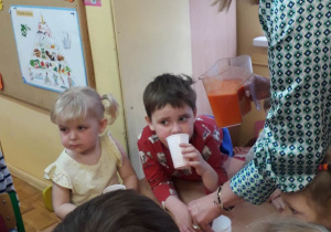 Dzieci piją sok marchewkowy.