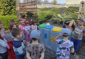 Dzieci oglądają pojemniki do segregacji śmieci.
