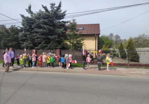 Dzieci spacerują z flagami po ulicy Wąwalskiej .