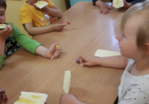 Dzieci jedzą miód z wafelkami.
