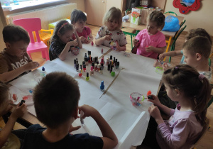 Dzieci wspólnie wybierają lakiery do malowania butelek.
