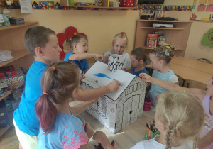 Dzieci zaczynają malować domek marzeń.
