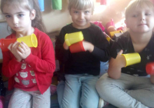 Dziewczynki wystukują rytm muzyki na plastikowych kubeczkach