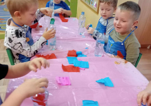 Dzieci wkładają do butelki z wodą bibułe