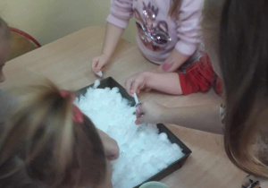 Dziewczynki bawią się w szukaniu skarbów w śniegu