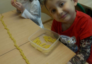 Dzieci robią łańcuch z makaronu