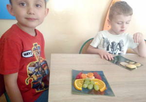Chłopcy układają zwierzątka z owoców i warzyw