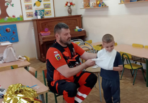 Pan ratownik pokazuje udzielanie pierwszej pomocy w przypadku złamania ręki.