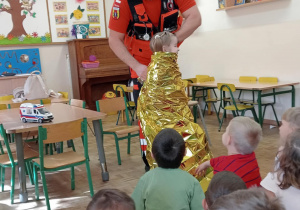 Pan ratownik pokazuje koc ratunkowy.