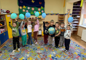 Dzieci stoją z globusem i balonami w kolorach naszej planety.