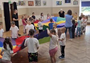 Dzieci biorą udział w zabawie z chustą animacyjną.