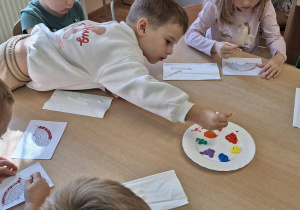 Przedszkolaki wykonują pracę plastyczną " Tęczowe kropki".