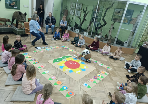 Dzieci siedzą na podłodze podczas warsztatów w muzeum.