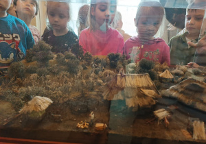 Dzieci stoją przed gablotą muzealną.