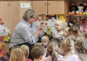 Pani pokazuje dzieciom miód w słoikach.