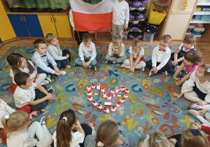 Starsze dzieci siedzą na dywanie.