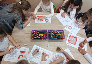 Dziewczynki kolorują flagę i godło Polski.