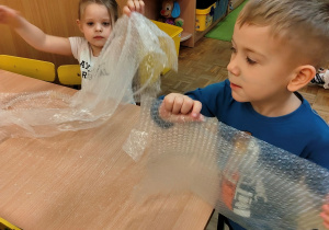 Dzieci bawią się folią bąbelkową.