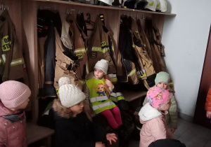 Dzieci w szatni strażaków oglądają mundury.