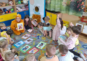Pani bibliotekarka pokazuje dzieciom obrazki z misiami.
