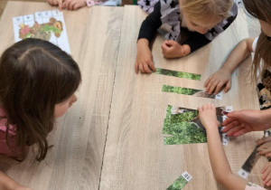 Dzieci układają układankę.