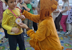 Pani bibliotekarka zakłada medal chłopcu.