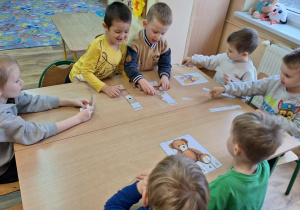 Chłopcy układają postacie misia z wyciętych pasków.