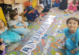 Przedszkolaki bawią się na dywanie.